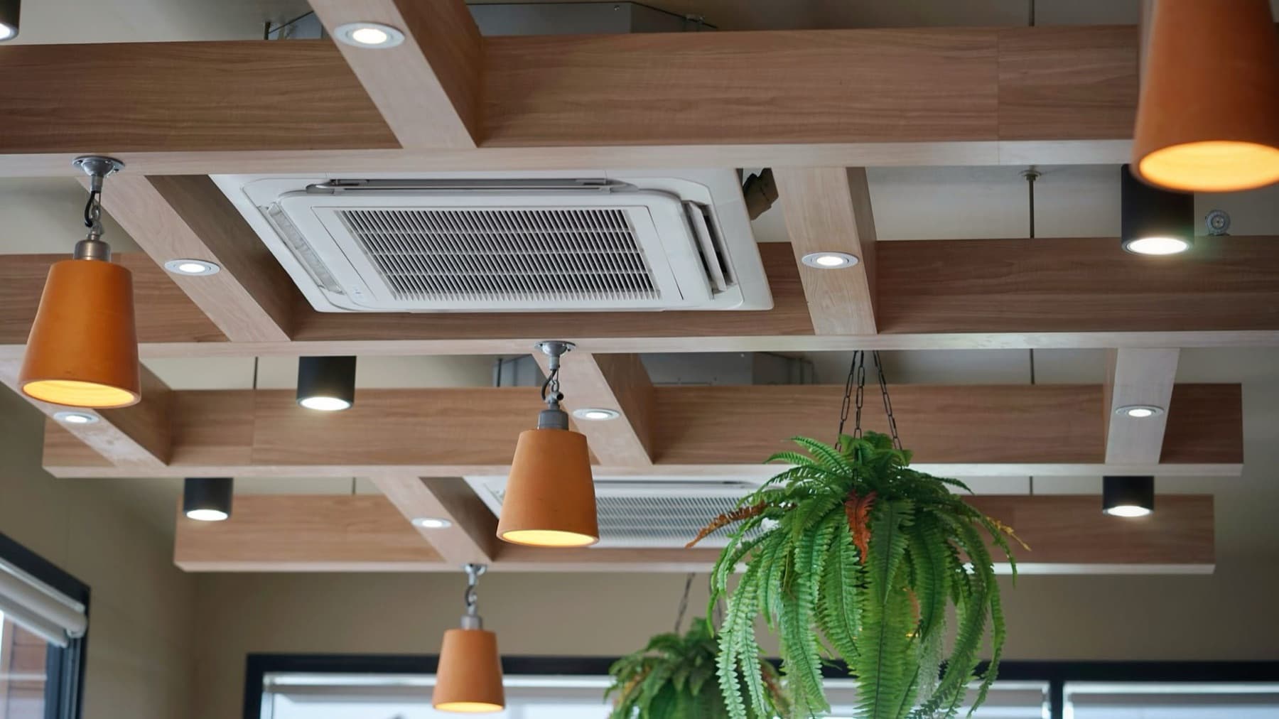Unidades de aire acondicionado tipo cassette integradas en el techo de madera de un local