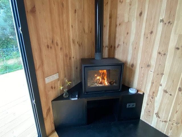 Estufa de leña encendida en un salón revestido de madera