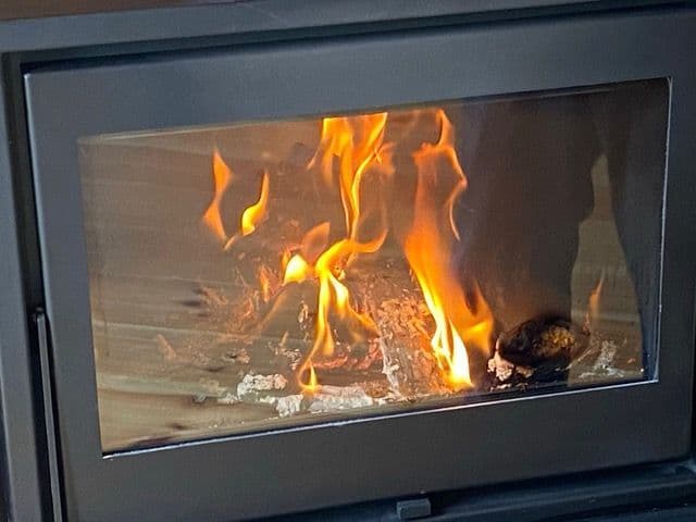Fuego vivo dentro de una estufa de leña tipo casete con el cristal limpio