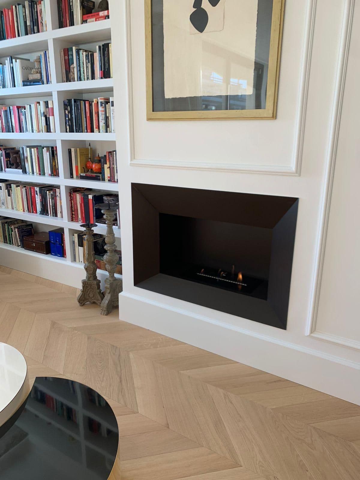 Chimenea de bioetanol integrada junto a una librería blanca
