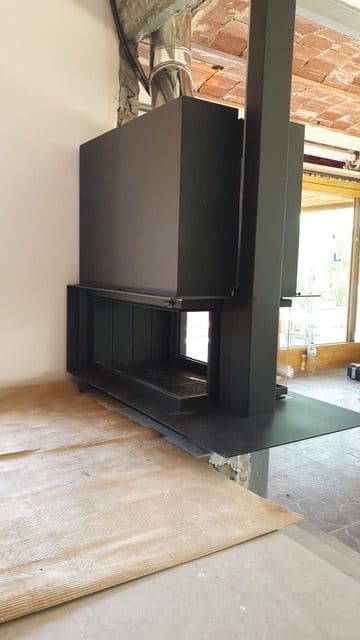 Chimenea de leña de tres caras hecha a medida con puerta guillotina, durante la instalación