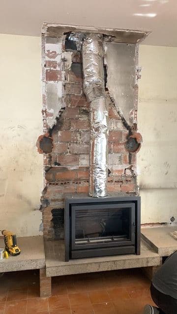 Casete de leña encajado en el hueco de una chimenea de ladrillo durante la obra